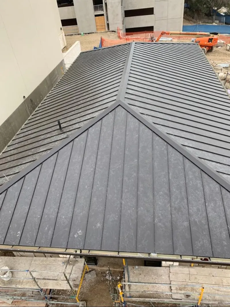 Commercial metal roof construction with crane equipment in Demarest